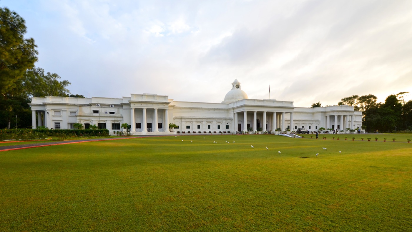 The main administrative building of IIT Roorkee: a long white colonial building with columns, a central dome and clock tower, fronted by a wide green lawn.